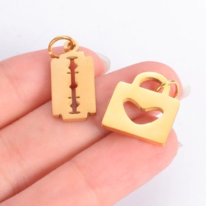 Gold stainless steel razor blade and heart padlock pendants held on a palm