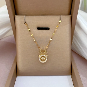 Close-up of golden antler necklace with dancing zircon stones in a beige jewelry box