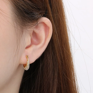 Close-up of gold-plated U-shaped earrings with pavé-set shimmering zircon stones