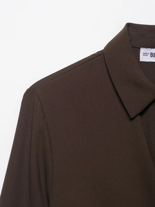 Detail of dark brown crepe fabric shirt showing collar texture and shoulder stitching