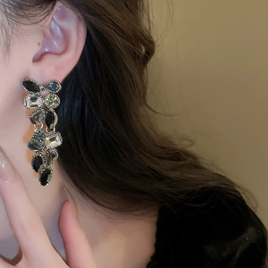 Close-up of elegant long drop earrings with dark multifaceted crystals on a female model