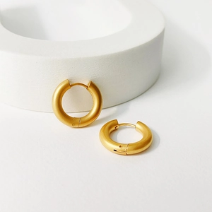 Close-up of golden matte thick hoop earrings with textured finish and hinge closure