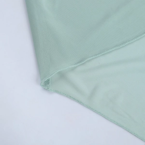 Détail macro du tissu en maille vert menthe montrant le tricot et la couture de l'ourlet
