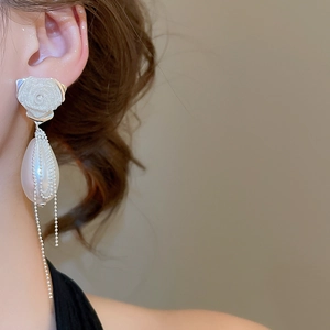 Close-up of white rose earring with drop pearl and delicate silver beaded tassels