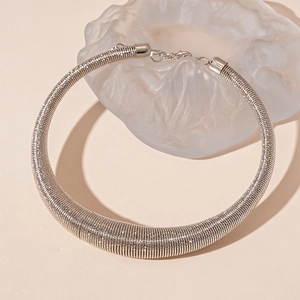 Macro shot of silver textured thick metal collar necklace with intricate wire wrapping details