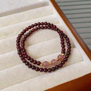 Close-up of garnet and strawberry quartz beaded bracelets with gold spacers in a jewelry box