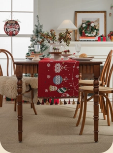 Detail view of red Christmas table runner with festive jacquard patterns and tassels