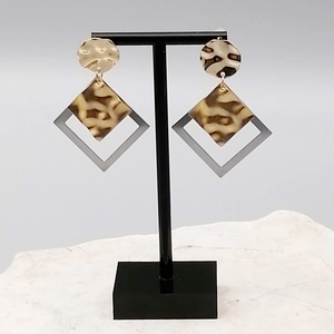 Macro detail of long earrings featuring gold metal and brown leopard print elements