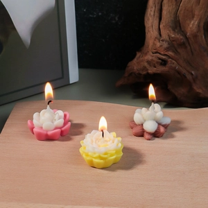 Three lit lotus flower candles in pink and yellow on a wooden tray for home decor