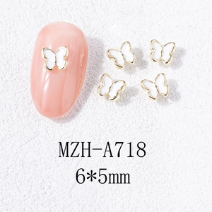 Vue macro de breloques papillon 6x5mm pour ongles avec bord doré et échantillon d'ongle