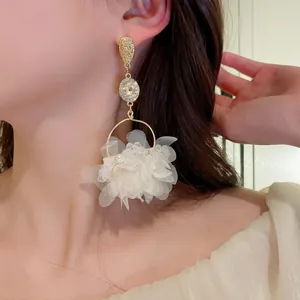 Elegant floral tassel earrings with white organza petals and gold crystal studs on model