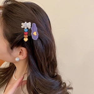 Model wearing purple flocked duckbill hair clips and cartoon bear side pins on hair