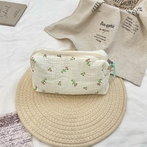 Detail of floral cotton makeup bag with red roses on a rustic straw mat setup