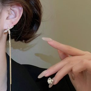 Vue macro de boucles d'oreilles pompons dorées avec étoiles en zircon portées sur l'oreille