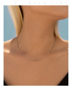 Close-up of a minimalist S925 sterling silver snake chain necklace on a model's neck
