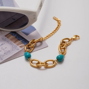 Detailed macro shot of gold thick chain bracelet featuring blue turquoise stone beads