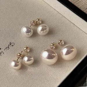 Detailed close-up of three pairs of elegant white pearl stud earrings on a beige fabric tray