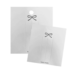 Minimalist white handmade jewelry display card with black bow and hanging hole for earrings