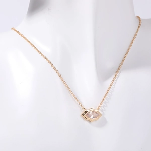 Dettaglio della collana con ciondolo occhio in oro e zircone trasparente su busto bianco