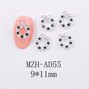Detail of Christmas nail art charms with green rhinestones and pearls in a wreath shape