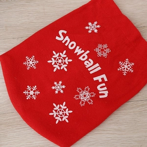 Red plush Snowball Fun bag with white snowflakes for Christmas decoration on wood surface