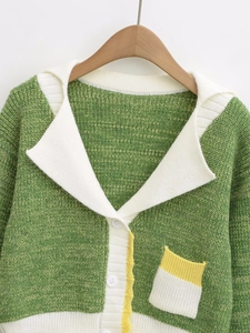 Close-up of green and white knit cardigan featuring detailed texture and white buttons