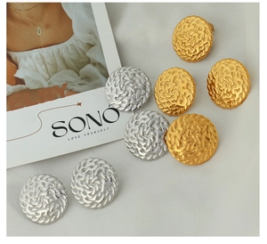 Detailed view of round metal earrings with vintage woven texture in gold and silver