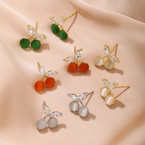 Exquisite cherry opal earrings in green, orange, beige, and grey on peach silk background