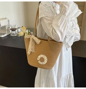 Detail of hand-woven khaki tote bag with lace bow and daisy patch in a cafe setting