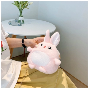 Detail showing plush pink rabbit crossbody bag with golden chain strap on a model