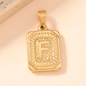 Detailed macro view of a gold square letter F pendant with polished metal texture