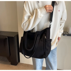 Black corduroy tote bag showing large capacity and adjustable shoulder strap on model