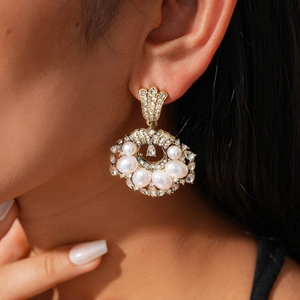 Detail of vintage gold fan-shaped earring with white pearls and sparkling rhinestones