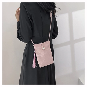 Detail of pink pleated leather crossbody bag featuring a pearl clasp and silk tassel