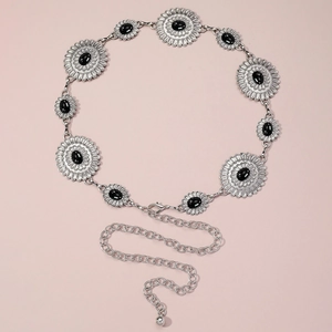 Macro detail of silver sunflower chain belt with black gemstone inlays and lobster clasp