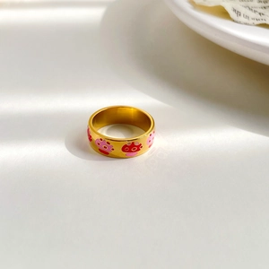 Close-up of gold stainless steel ring with colorful pink and red mushroom patterns