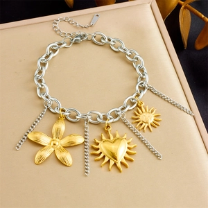Detailed shot of stainless steel charm bracelet with flower and sun pendants on metal board