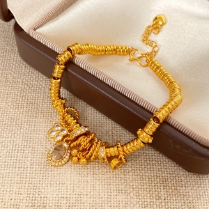 Detail of a 24k gold plated clover bracelet with oval zircon and sparkling charms