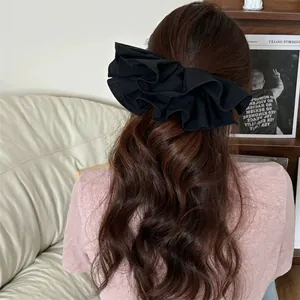 Elegant black oversized layered ruffle scrunchie for women shown on long wavy hair