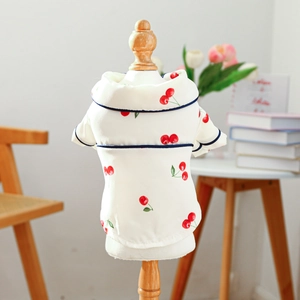 Detail view of pet pajamas with red cherry print and navy blue trim on white fabric