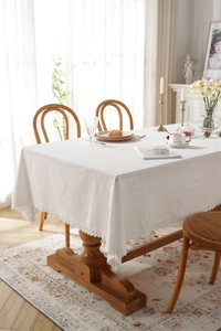 Detailed view of white cotton tablecloth with elegant lace trim on a rustic dining table
