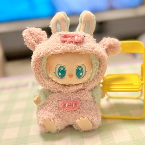 Detailed view of pink and green plush pig outfit on a doll beside a tiny yellow chair