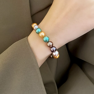 Détail d'un bracelet en perles colorées au poignet avec d'élégantes perles dorées et brunes