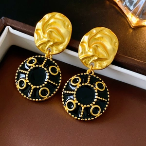 Macro detail of vintage black and gold floral earrings with a hammered metal texture finish