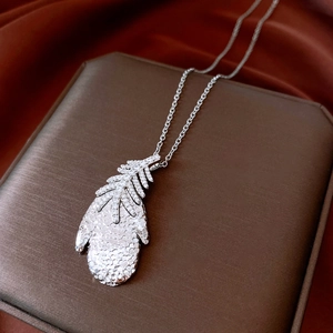 Detailed macro view of a silver feather necklace with zircon on a velvet gift box