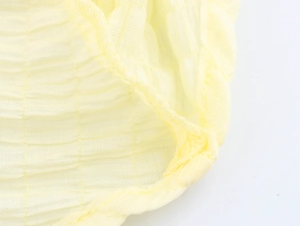 Macro shot of yellow textured crepe fabric with detailed stitching on the asymmetrical hem