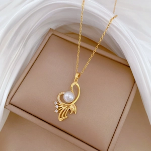 Elegant gold necklace with eagle wing pendant, pearl and crystals on silk background