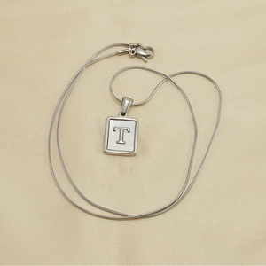 Détail du pendentif carré lettre T avec nacre sur une chaîne serpent en acier inoxydable