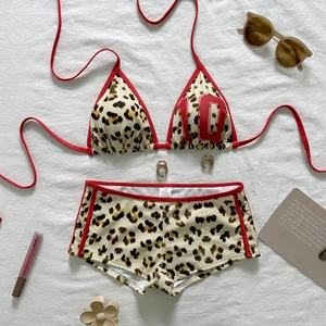 Flat lay of leopard print bikini with red trim, number 10 detail and summer accessories