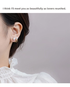 Detail of double pearl earrings in C-shaped gold finish worn by a model in lace dress